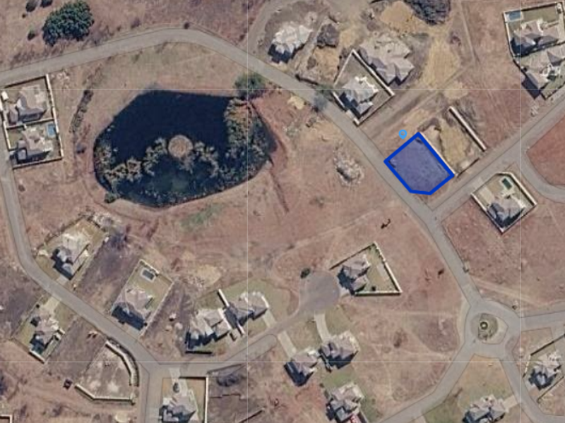 An aerial view of a vacant residential plot within a developed estate, highlighting the property boundaries and surrounding neighborhood layout.