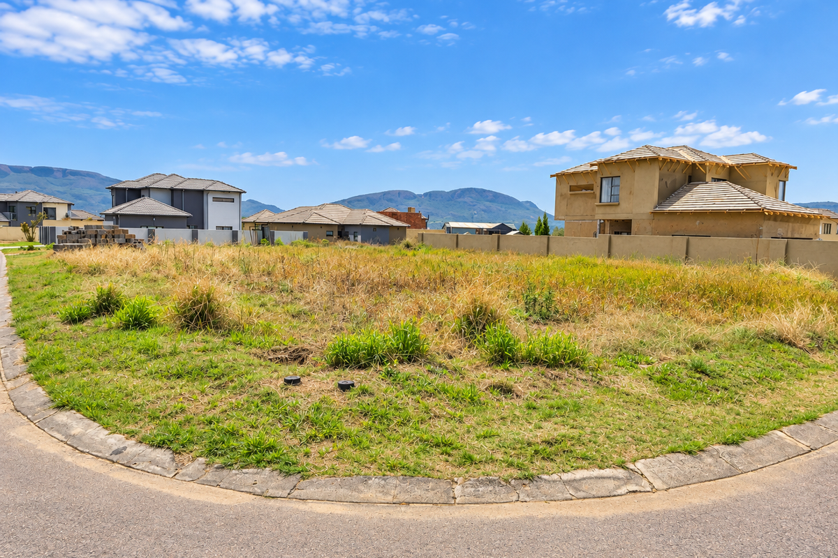 A vacant residential plot situated on a corner lot, featuring established boundary walls and mountain views in a developing neighborhood.
