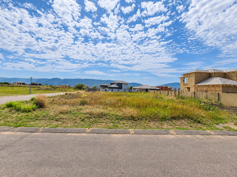 A vacant residential plot situated in a developed estate, featuring mountain views and proximity to existing residential properties.