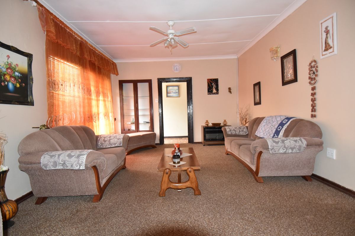 A comfortable living room featuring carpeted flooring, a ceiling fan, and a built-in display cabinet, offering a functional and traditional living space.