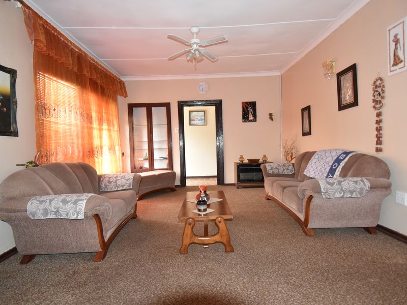 A comfortable living room featuring carpeted flooring, a ceiling fan, and a built-in display cabinet, offering a functional and traditional living space.