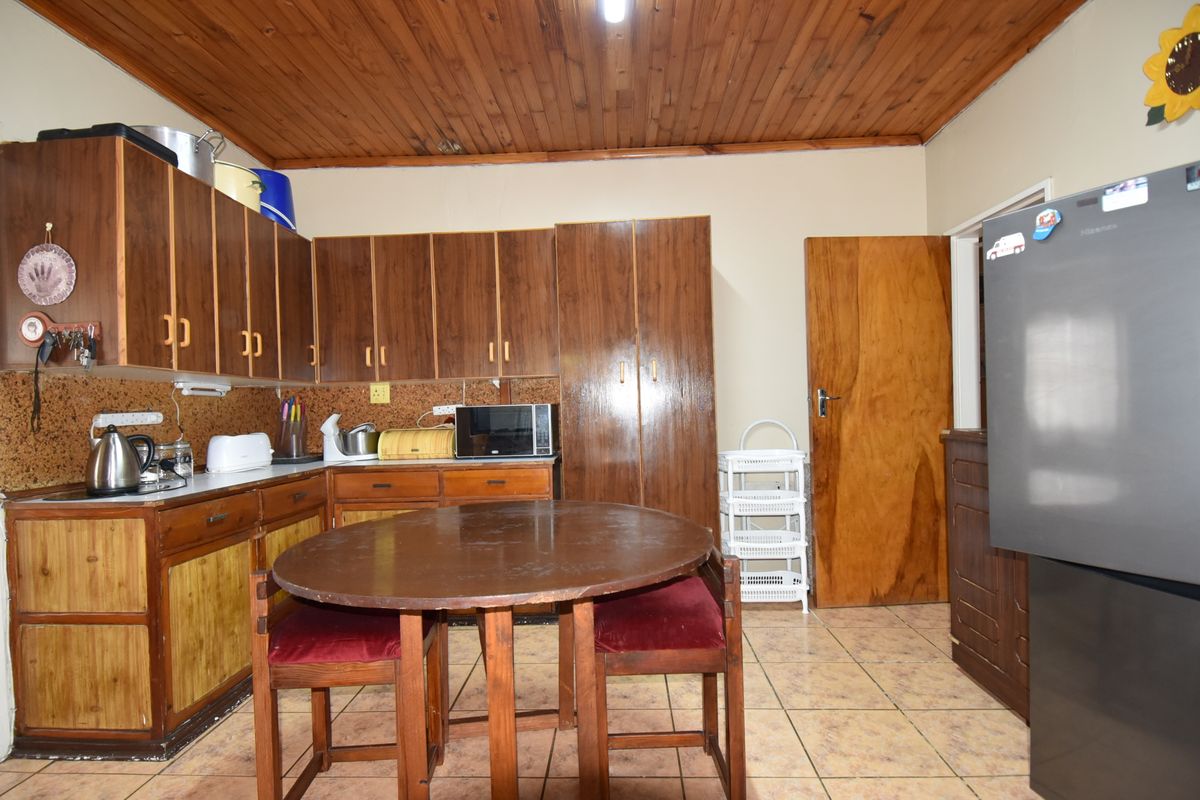 A functional kitchen featuring wooden cabinetry, tiled flooring, and a timber ceiling, offering a traditional aesthetic with potential for modern updates.