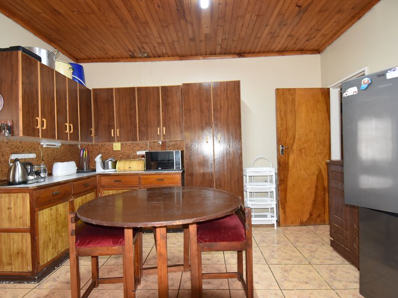 A functional kitchen featuring wooden cabinetry, tiled flooring, and a timber ceiling, offering a traditional aesthetic with potential for modern updates.