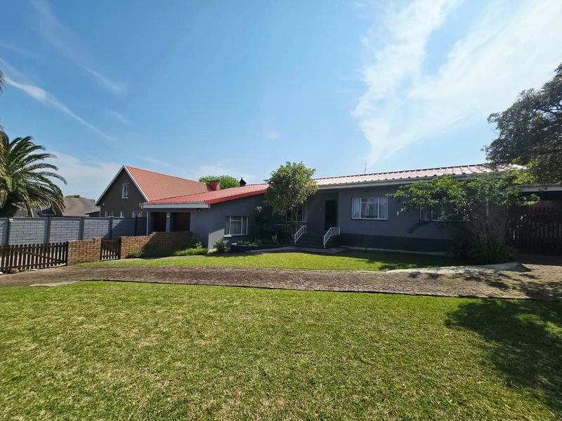 A well-maintained single-story residential property featuring a metal roof, paved driveway, and established front garden with secure boundary walling.