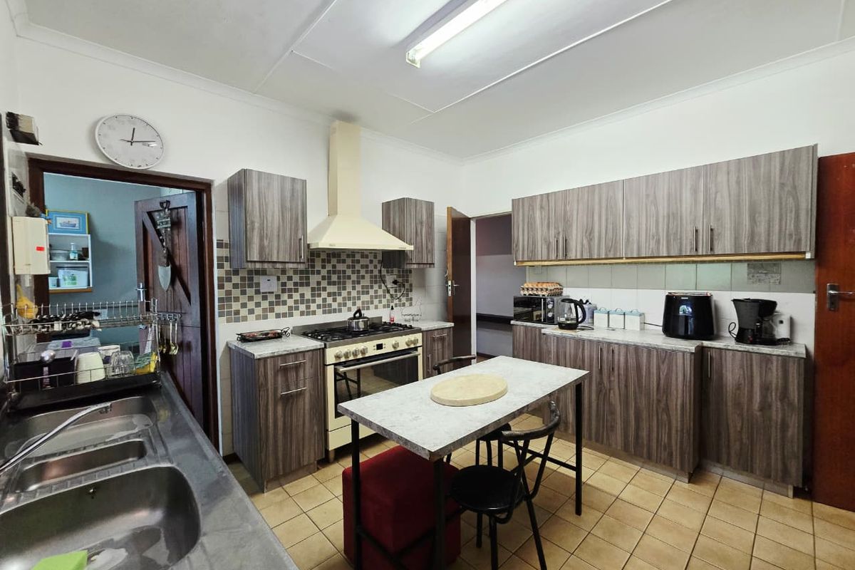 Functional kitchen featuring wood-grain laminate cabinetry, stone-look countertops, a gas stove with extractor fan, and a double stainless steel sink.