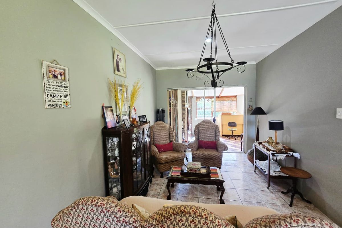 A living room featuring tiled flooring, a decorative wrought iron chandelier, and a sliding glass door providing access to an outdoor area.