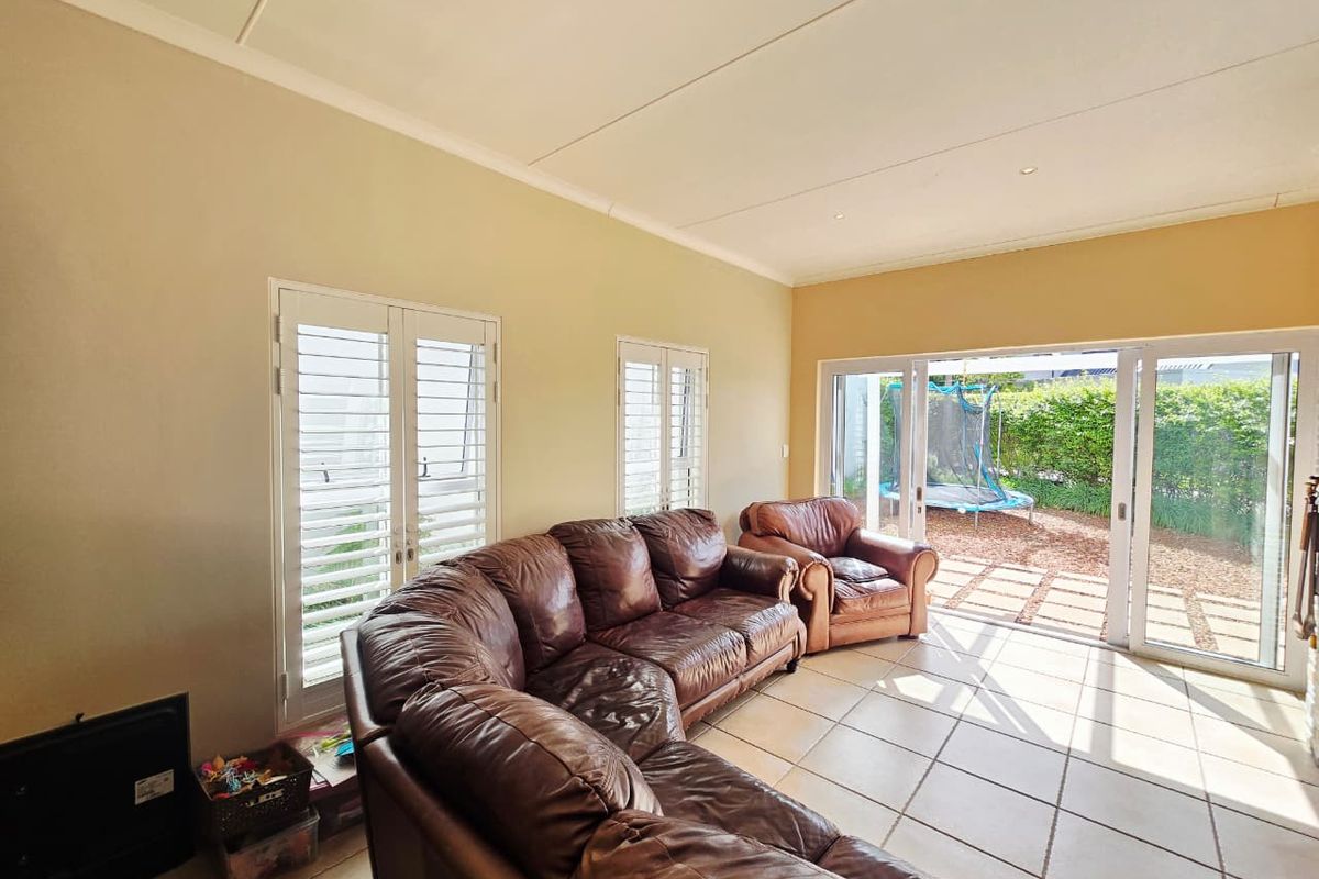 Bright living room featuring tiled flooring, recessed lighting, and large sliding glass doors providing seamless access to the outdoor patio area.