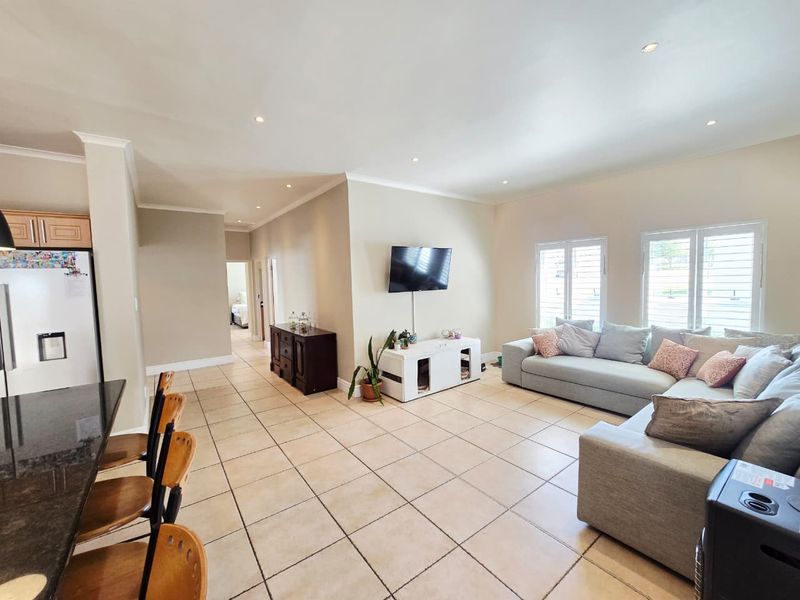 Spacious open-plan living area featuring tiled flooring, recessed lighting, and a kitchen island, seamlessly connecting the kitchen and lounge space.