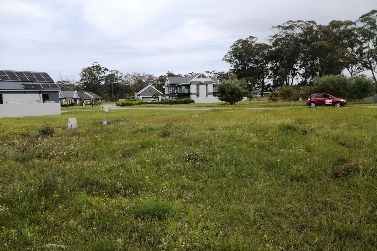 A view of a vacant residential plot in a suburban estate, featuring surrounding homes and established greenery.