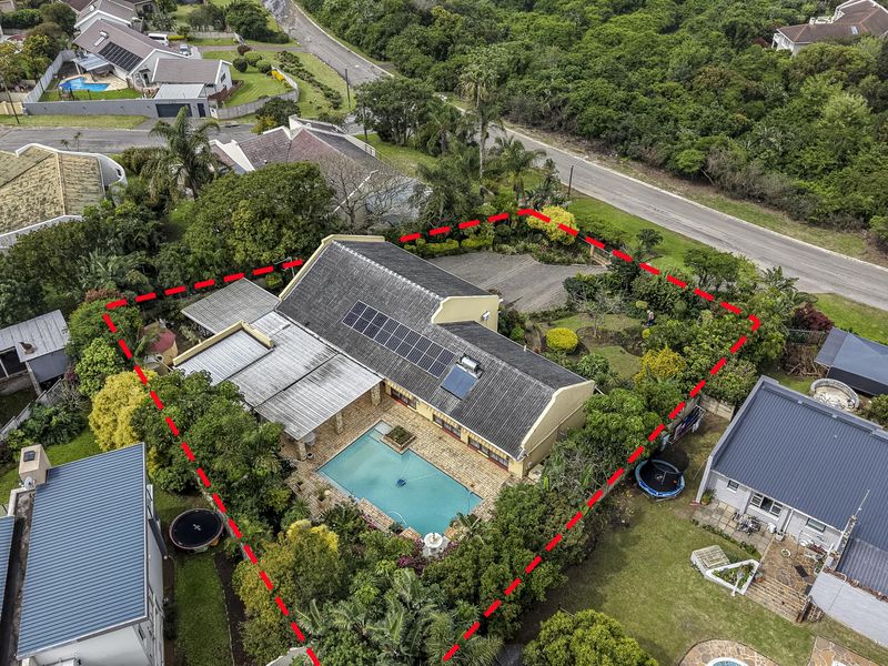 Aerial view of a residential property featuring a swimming pool, solar panels, paved patio area, and established garden within a suburban setting.