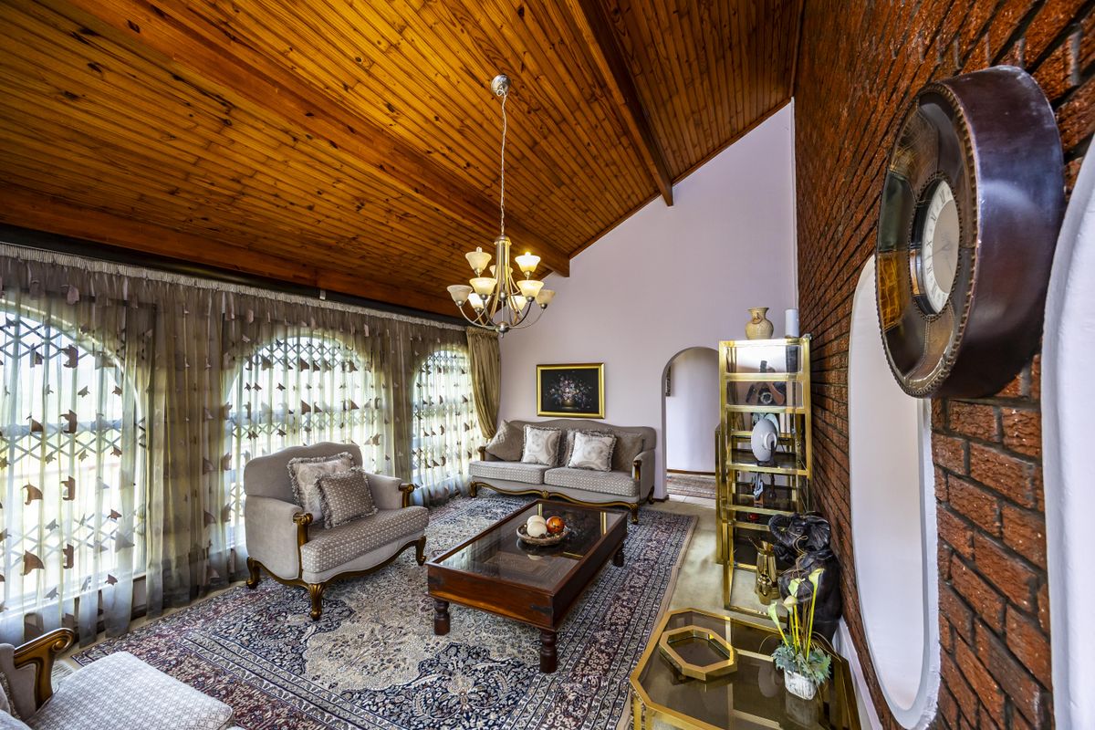 Spacious living room featuring a high raked timber ceiling, exposed brick wall, and arched windows, creating a warm and character-filled atmosphere.