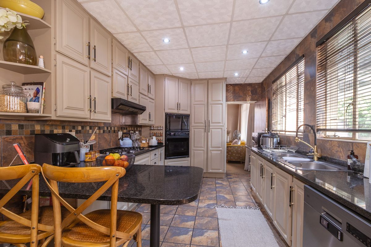 A well-maintained kitchen featuring granite countertops, built-in cabinetry, integrated appliances, and tiled finishes, offering a functional and classic cooking space.