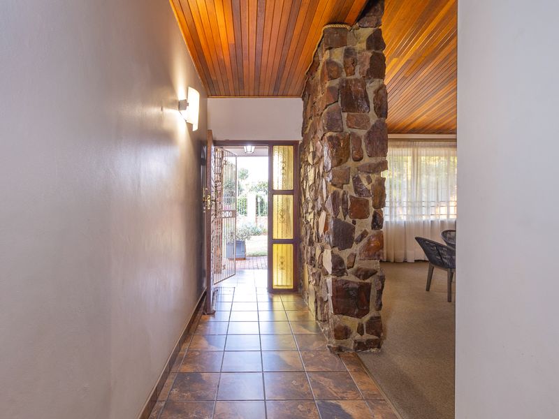Entrance hall featuring a rustic stone feature wall, warm timber ceiling, and tiled flooring, leading directly into the main living area.