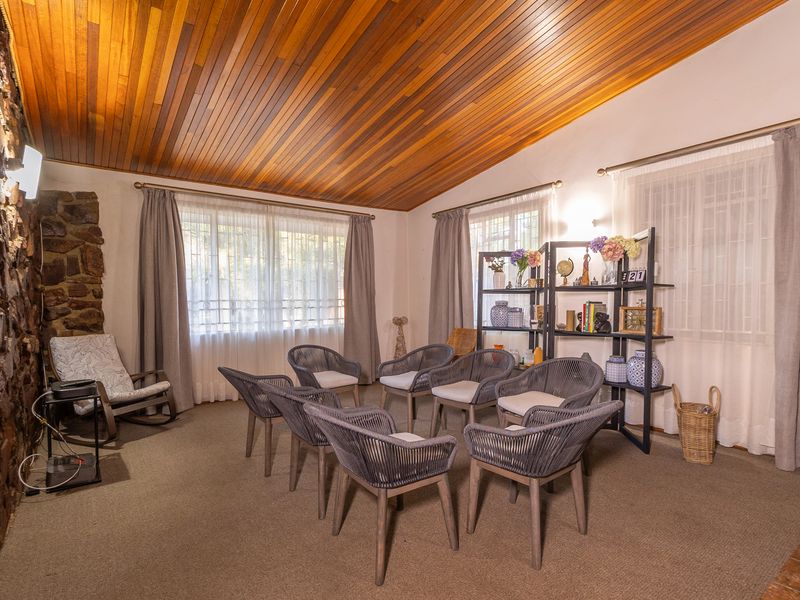 A spacious living room featuring a distinctive timber-clad vaulted ceiling and a rustic natural stone feature wall, offering a warm and textured aesthetic.