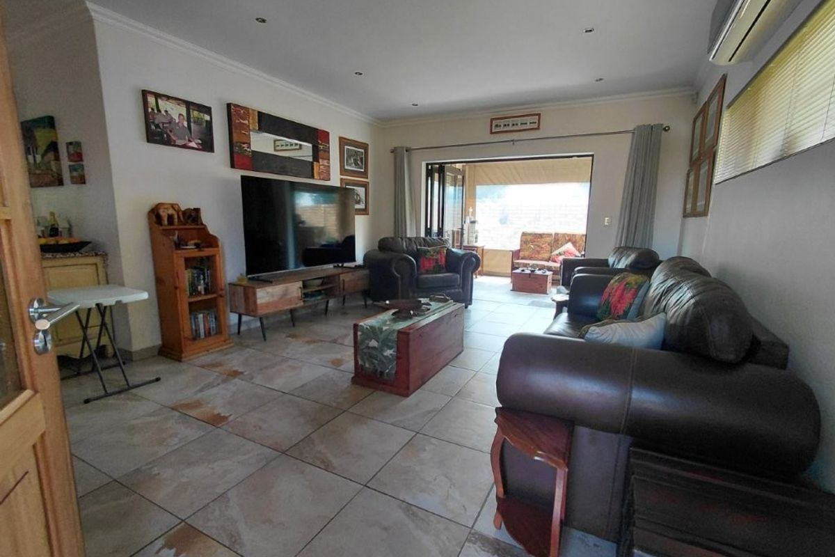 Spacious living room featuring large format floor tiles, recessed lighting, and direct access to an outdoor patio area through sliding glass doors.