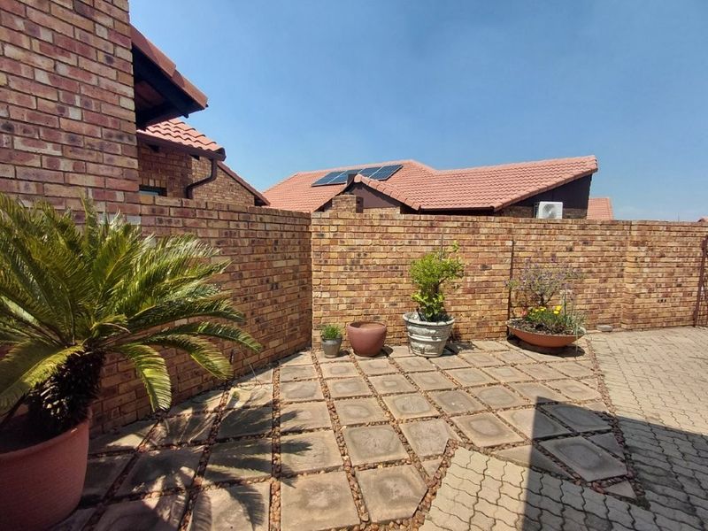 A private rear courtyard featuring face brick boundary walls and paved flooring, with solar panels visible on the adjacent roof structure.