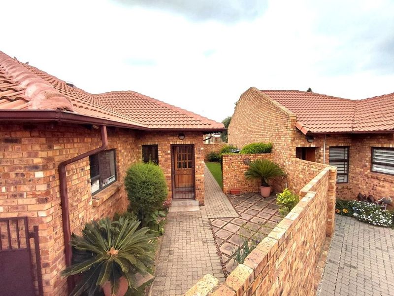 A view of the rear exterior featuring face brick construction, tiled roofing, and a paved walkway leading to a timber entrance door.