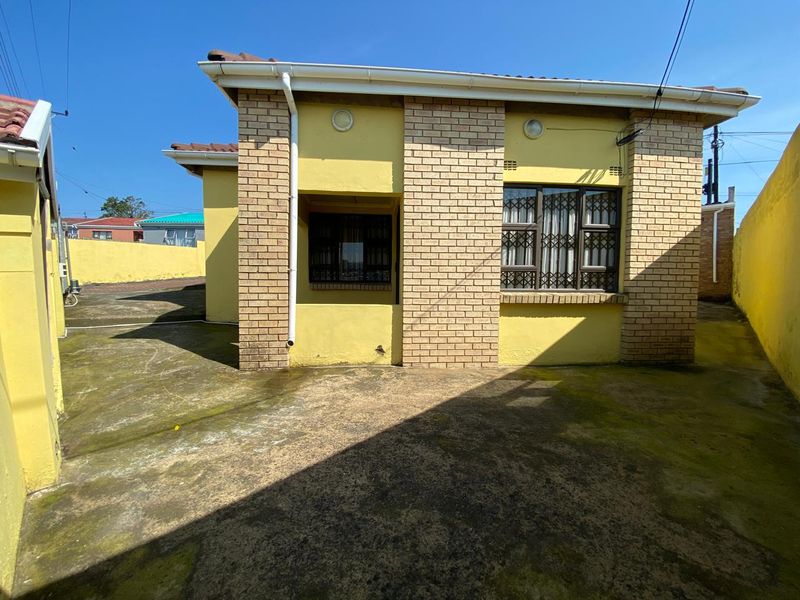 Rear exterior view of the property featuring brick facade, security bars on windows, and a paved courtyard area.