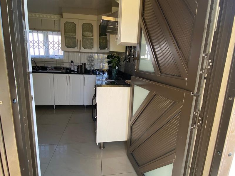 A functional kitchen featuring white cabinetry, dark countertops, and tiled flooring, accessed through a secure metal door.