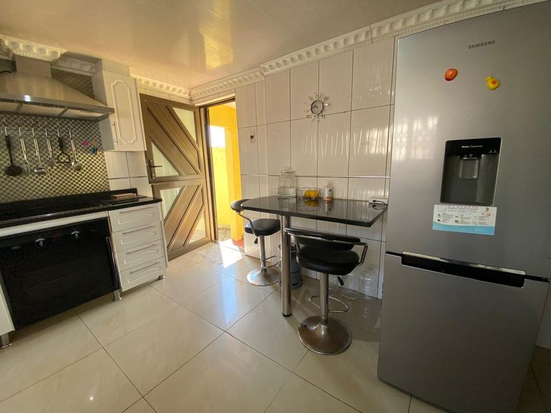 A functional kitchen featuring tiled walls and flooring, built-in cabinetry, granite countertops, and an integrated oven with an extractor fan.