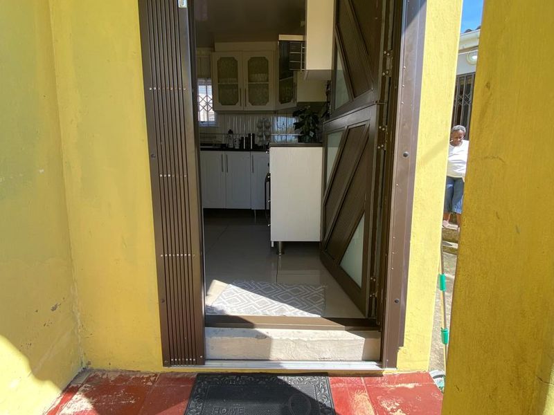 View from the entrance porch looking into a kitchen area, featuring a security gate and tiled flooring.