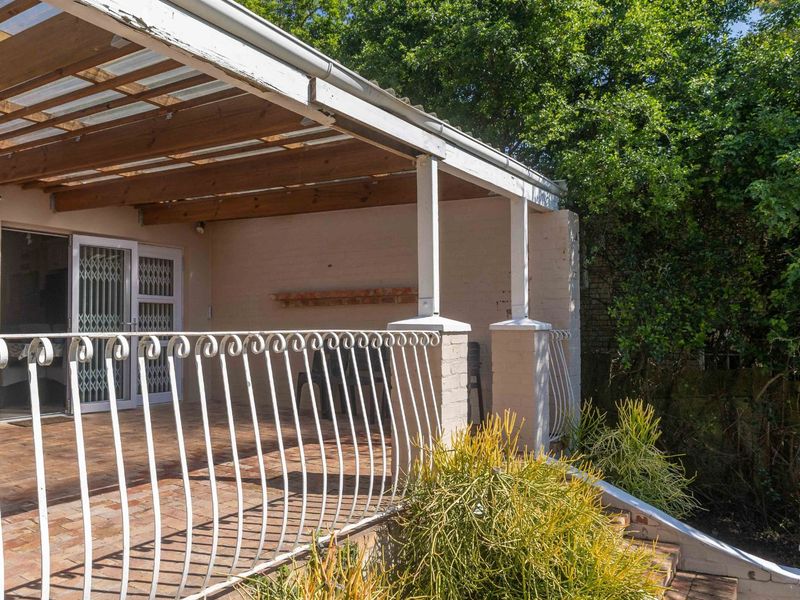 Covered outdoor patio area featuring brick paving, a timber pergola, and wrought iron railings, providing a functional space for outdoor relaxation.