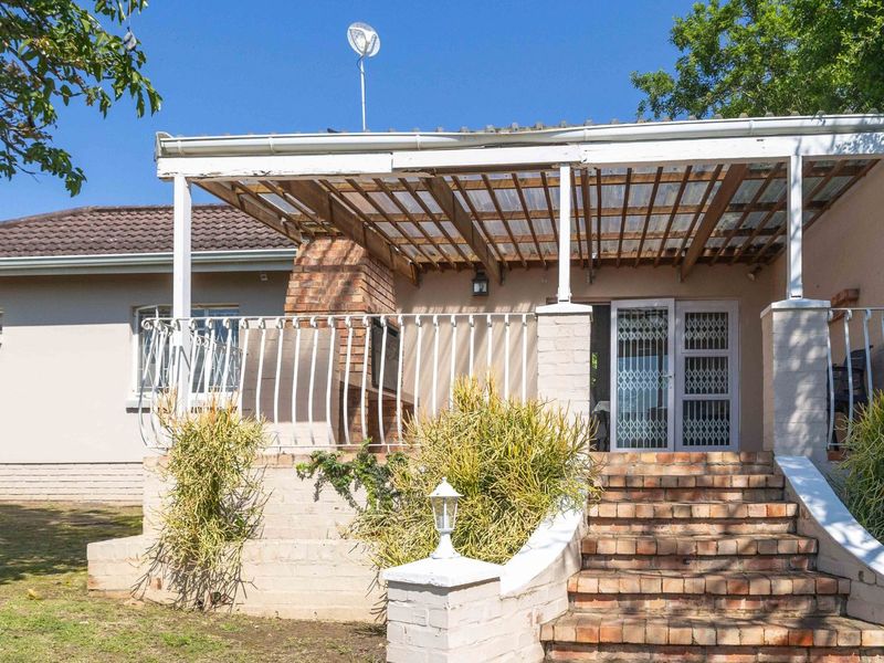 A covered outdoor patio featuring a built-in brick fireplace, brick staircase, and security gate, offering a functional space for outdoor entertaining.