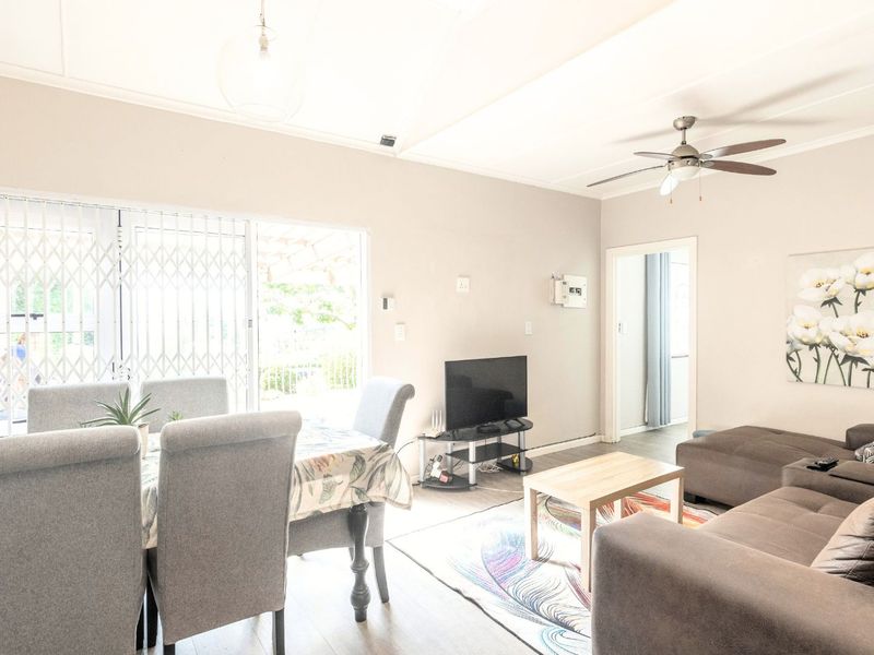 An open-plan living and dining area featuring laminate flooring, a ceiling fan, and sliding glass doors leading to the exterior.