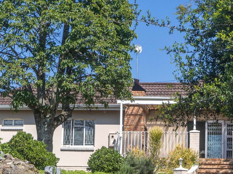Front elevation of a single-story house featuring a tiled roof, brick chimney, and a covered entrance area with security gates.