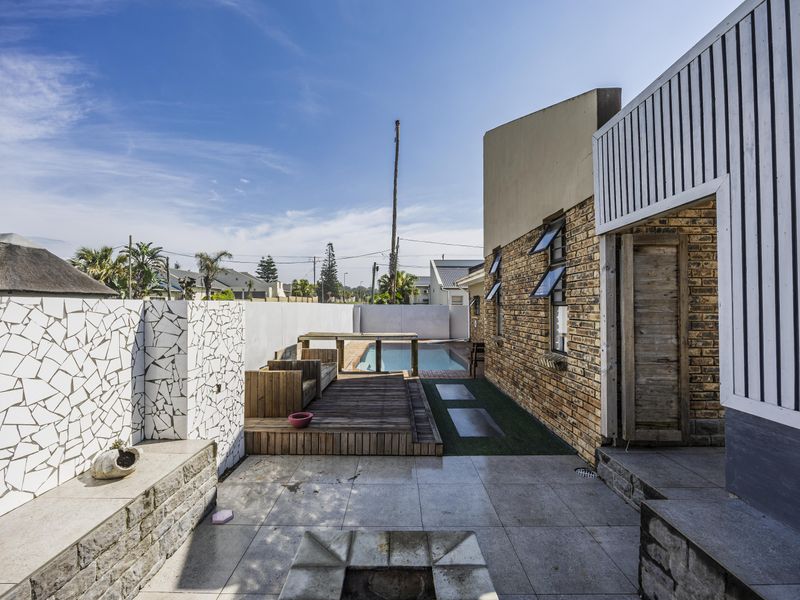 Outdoor entertainment area featuring a swimming pool, timber decking, stone patio, and a unique mosaic feature wall with built-in seating.