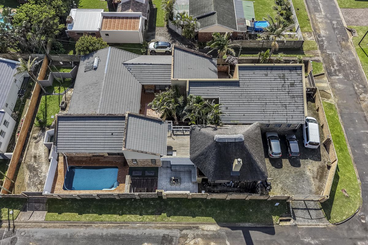 Aerial view of the property showcasing the main residence with a combination of tiled and thatched roofing, swimming pool, and paved driveway.