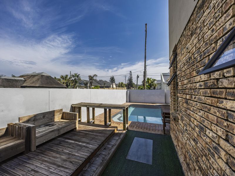 Outdoor pool area featuring a swimming pool, timber decking, and a brick exterior wall, enclosed by a boundary wall.