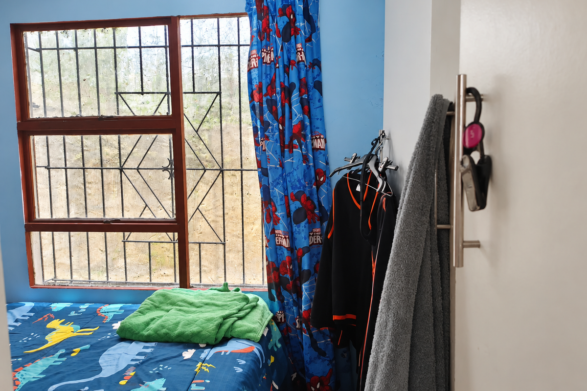 A bedroom featuring a window with security bars and blue wall paint.