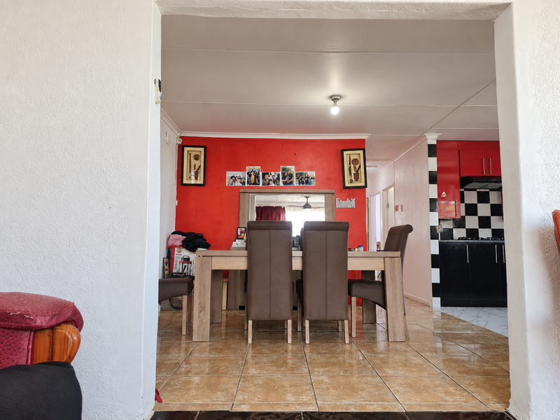 Open plan dining and kitchen area featuring tiled flooring, built-in cabinetry, and a checkerboard backsplash, offering a functional layout for daily living.