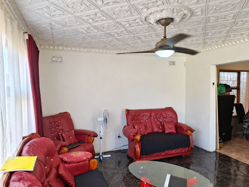 Living room featuring a distinctive ornate pressed metal ceiling, ceiling fan, and dark tiled flooring.