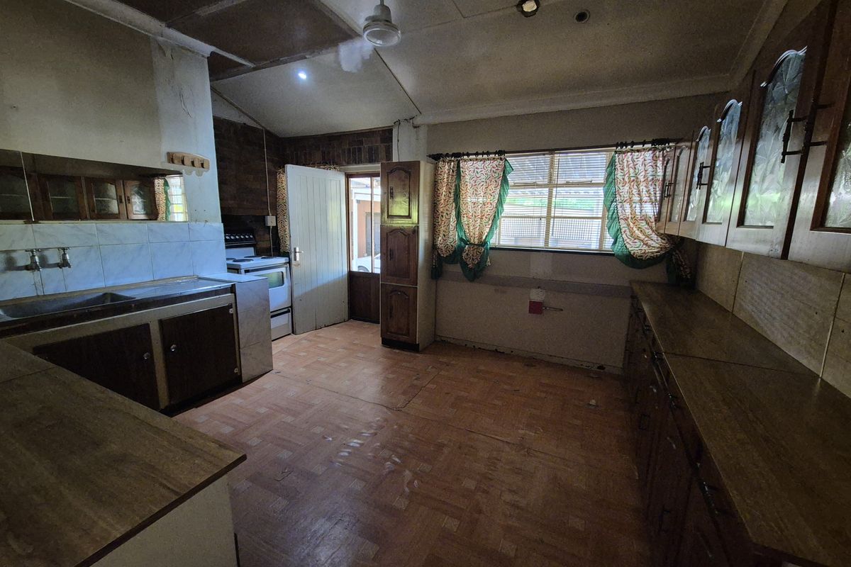 A dated kitchen featuring original built-in cabinetry, laminate countertops, and vinyl flooring, offering significant potential for a modern renovation.