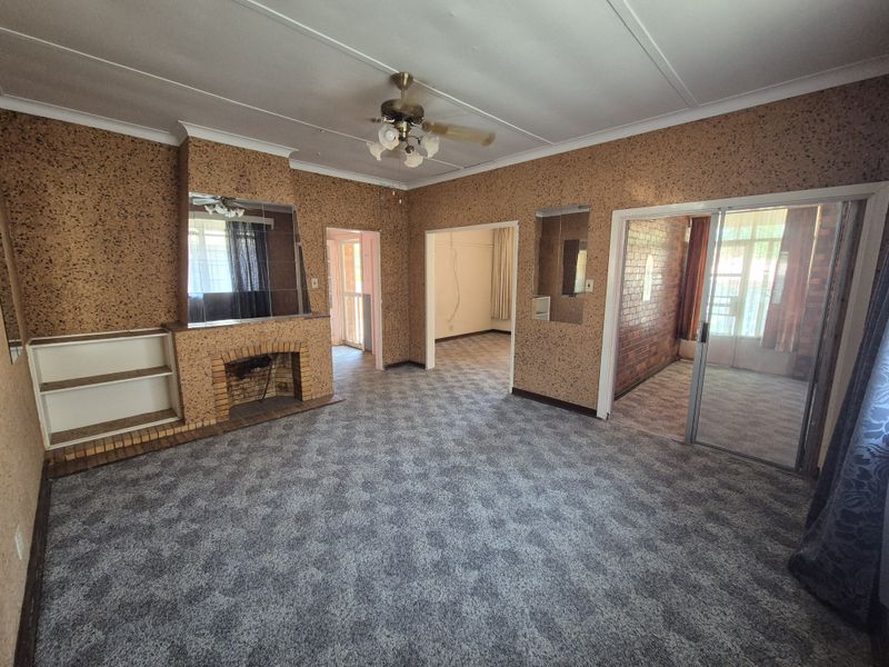 Spacious living room featuring a brick fireplace, built-in shelving, and sliding glass doors leading to an adjacent room.