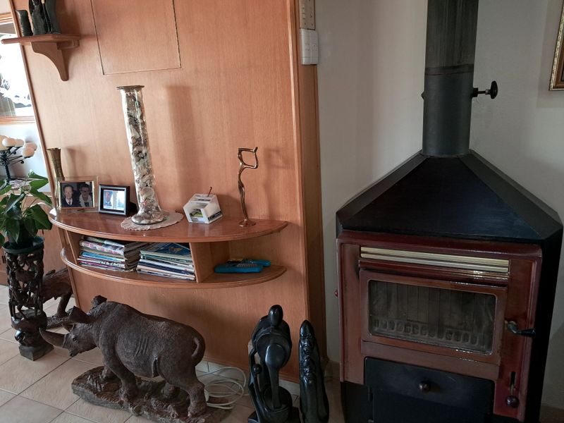 A living room area featuring a freestanding fireplace and built-in wooden shelving unit with tiled flooring.