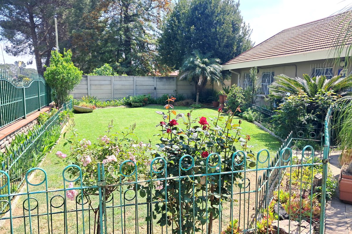 A well-maintained rear garden featuring a lush lawn, established landscaping, and secure perimeter fencing with a tiled roof house elevation.
