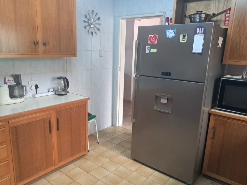 A functional kitchen featuring wooden cabinetry, laminate countertops, and ceramic tiling throughout.