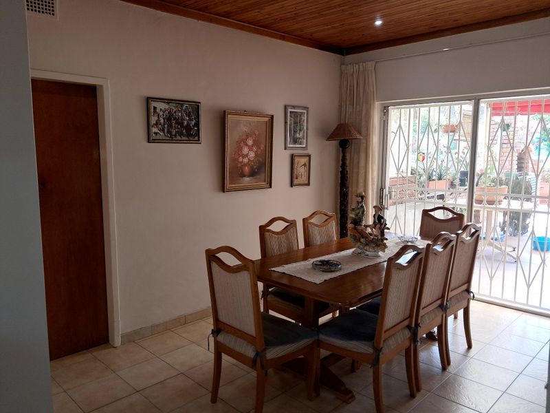 Dining room featuring tiled flooring, a timber ceiling, and a sliding glass door with a security gate leading to the patio.