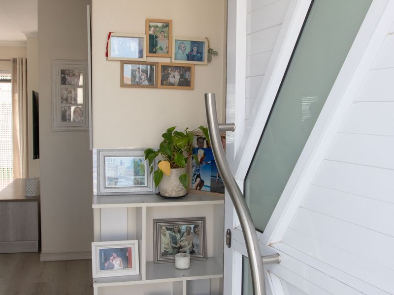 A bright and welcoming entrance area featuring a modern white panelled front door with a sleek stainless steel handle and light-toned laminate flooring.