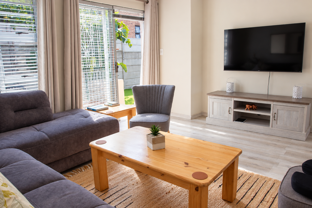 A bright and well-maintained living room featuring light laminate flooring and a large sliding glass door providing access to the outdoor area.
