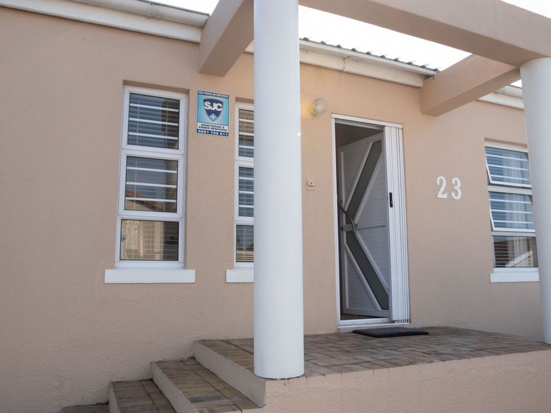 Front entrance of the house featuring a paved porch, concrete support columns, and a secure entrance door with an integrated security gate.