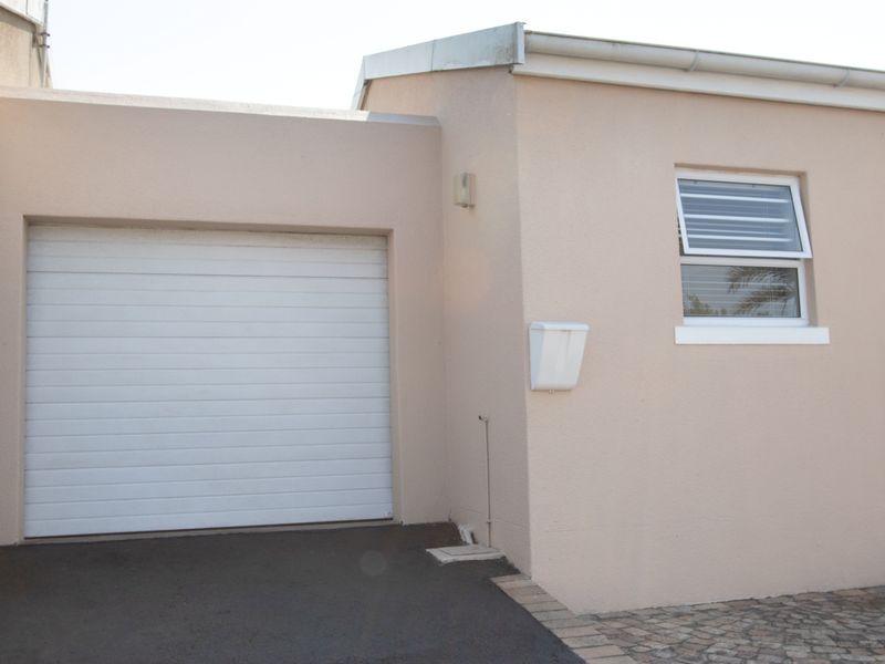 A clean exterior view of a single garage featuring a roll-up door, louvre window, and paved driveway access.