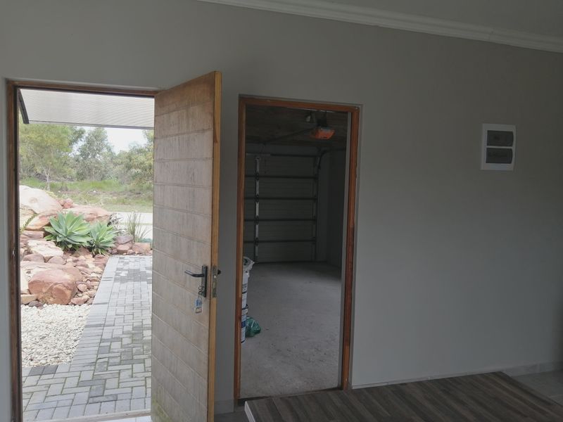 An entry area featuring a timber door opening to a paved outdoor space, with direct access to an attached garage.