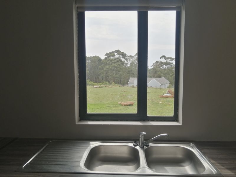 A kitchen sink area featuring a double bowl stainless steel sink with a mixer tap, set against a window with a scenic outdoor view.