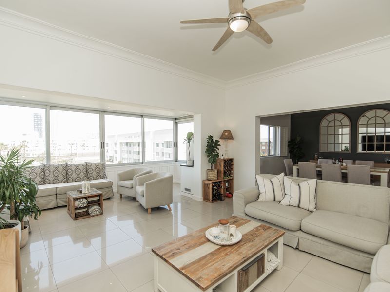 Spacious open-plan living and dining area featuring large sliding glass doors, polished tile flooring, and a modern ceiling fan.