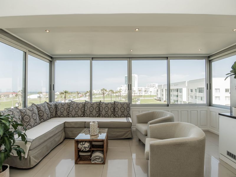 Bright and spacious living area featuring extensive floor-to-ceiling glass windows with panoramic views, recessed lighting, and polished tile flooring.