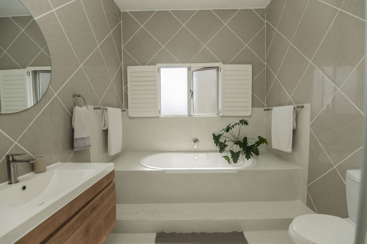Modern bathroom featuring a built-in bathtub, wall-mounted vanity with basin, and stylish diamond-patterned wall tiling.